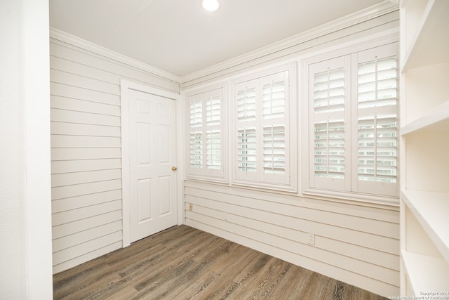 spare room featuring wood walls, crown molding, and dark hardwood / wood-style flooring