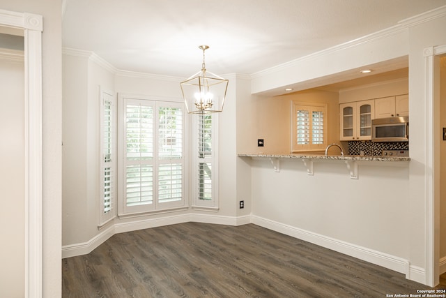 unfurnished dining area featuring crown molding, a chandelier, and dark hardwood / wood-style floors