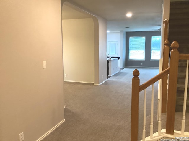 hallway with carpet floors, stairway, and baseboards