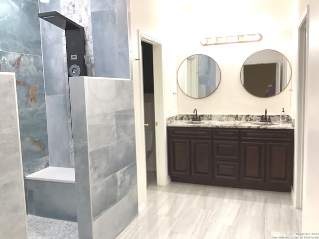 bathroom with double vanity, walk in shower, and a sink