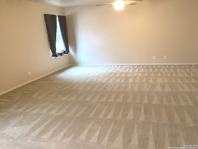 carpeted empty room with ceiling fan and baseboards