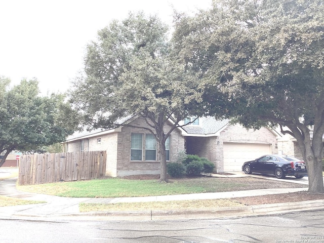 view of front of property with an attached garage, brick siding, fence, concrete driveway, and a front yard