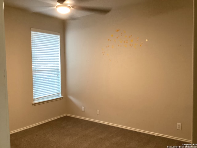 empty room featuring dark colored carpet and a ceiling fan