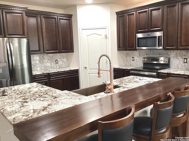 kitchen with appliances with stainless steel finishes, a sink, and tasteful backsplash