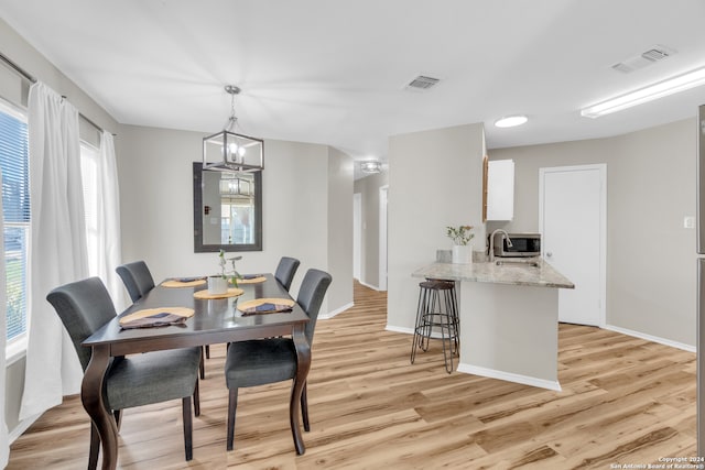 dining area with light hardwood / wood-style flooring, a notable chandelier, and a healthy amount of sunlight