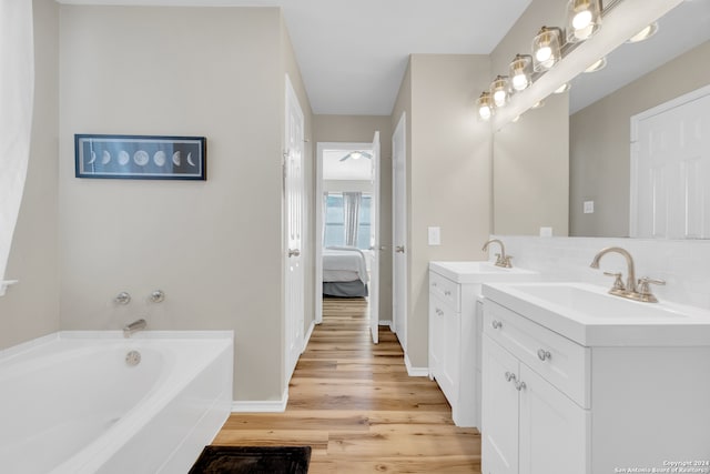 bathroom featuring vanity, backsplash, wood-type flooring, and a bathing tub