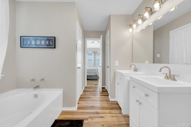 8722 Ridge Moon Dr, San Antonio, TX 78239 - ensuite bathroom with vanity, wood finished floors, a garden tub, tasteful backsplash, and baseboards