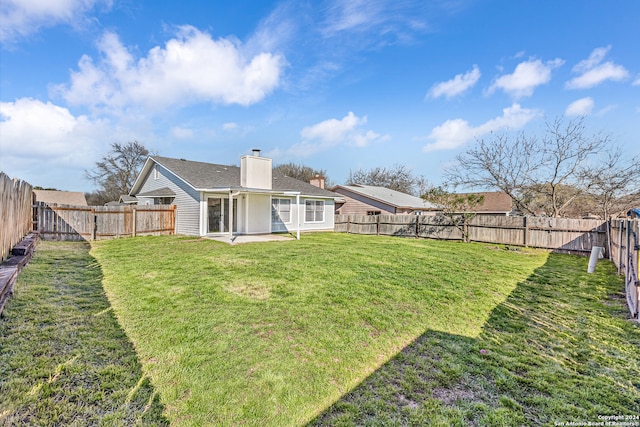 back of house with a yard and a patio