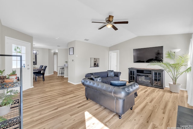 8722 Ridge Moon Dr, San Antonio, TX 78239 - living area with light wood-type flooring, ceiling fan, baseboards, vaulted ceiling, and a glass covered fireplace