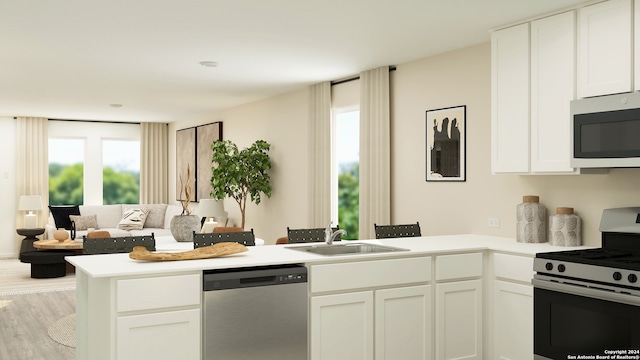 kitchen featuring light hardwood / wood-style flooring, kitchen peninsula, stainless steel appliances, sink, and white cabinets