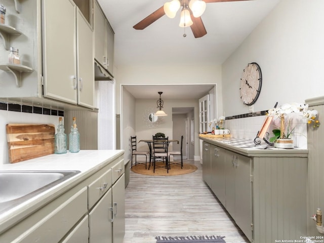 kitchen featuring decorative backsplash, ceiling fan, pendant lighting, gray cabinetry, and light hardwood / wood-style floors