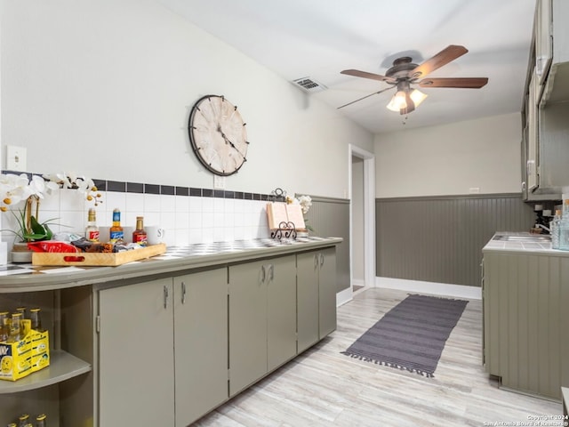 kitchen featuring tile countertops, light hardwood / wood-style flooring, sink, tasteful backsplash, and ceiling fan