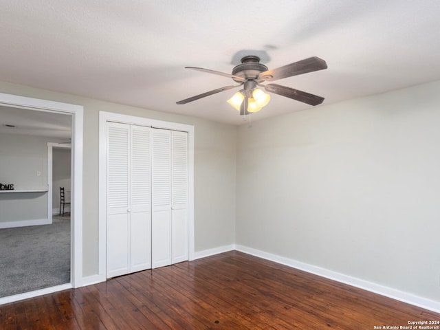 unfurnished bedroom featuring dark wood-type flooring, ceiling fan, and a closet