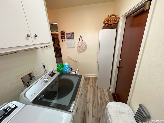 laundry area with independent washer and dryer, cabinets, and light wood-type flooring