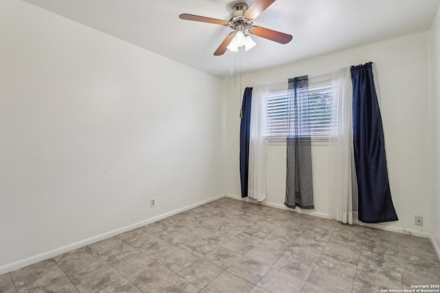 spare room featuring a ceiling fan and baseboards