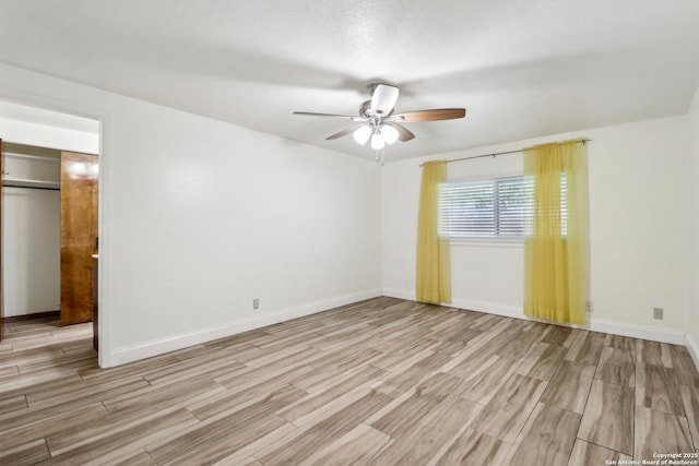 empty room with wood finished floors, ceiling fan, and baseboards