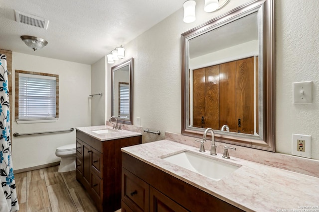 full bathroom with wood finished floors, visible vents, toilet, and a sink