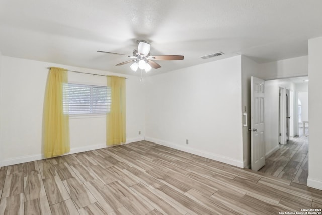 empty room with a ceiling fan, visible vents, baseboards, and light wood-style floors