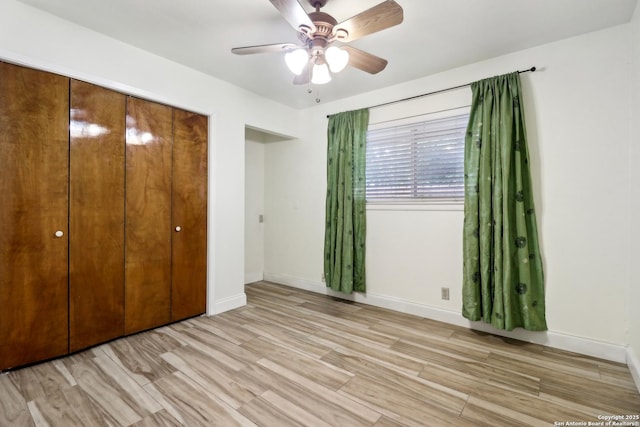 unfurnished bedroom with light wood finished floors, a closet, a ceiling fan, and baseboards