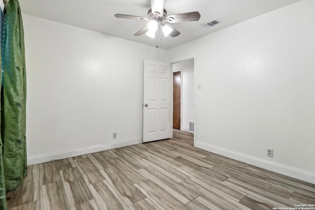 unfurnished room featuring light wood-type flooring, visible vents, a ceiling fan, and baseboards