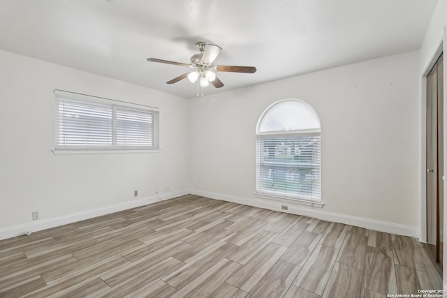 empty room featuring baseboards, a ceiling fan, and light wood-style flooring
