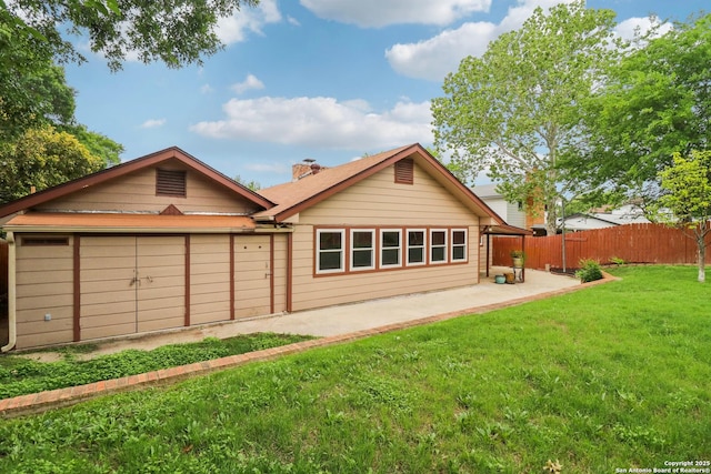 rear view of house with a patio, a lawn, a chimney, and fence