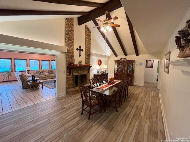 dining space with light hardwood / wood-style floors, beamed ceiling, a fireplace, high vaulted ceiling, and ceiling fan