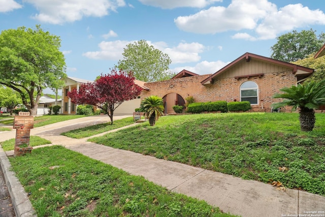 view of front of home with concrete driveway, a front lawn, an attached garage, and brick siding
