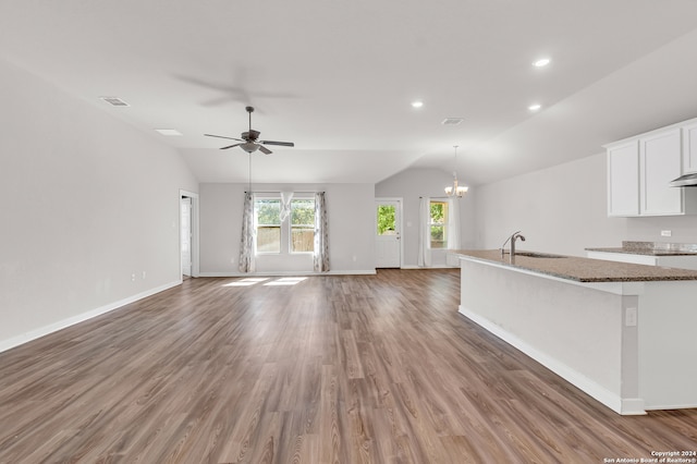 kitchen featuring dark wood-type flooring, vaulted ceiling, white cabinetry, and dark stone counters