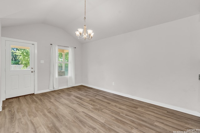 interior space with vaulted ceiling, light wood-type flooring, and an inviting chandelier