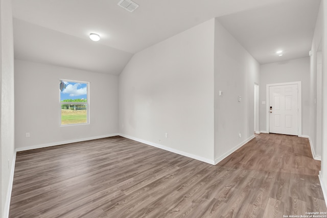 empty room with vaulted ceiling and hardwood / wood-style floors