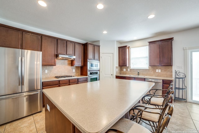 3718 Willow Walk, San Antonio, TX 78259 - kitchen featuring stainless steel appliances, under cabinet range hood, a kitchen island, decorative backsplash, and light countertops