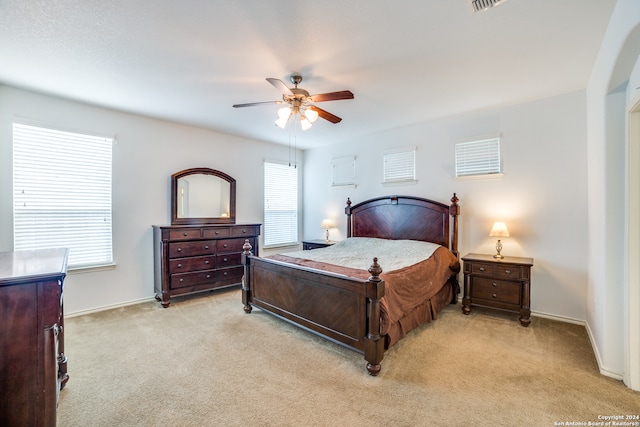 bedroom featuring ceiling fan, multiple windows, and light colored carpet