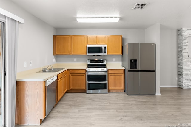 kitchen featuring sink, appliances with stainless steel finishes, light hardwood / wood-style flooring, and a textured ceiling