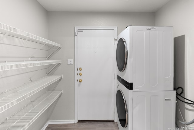 washroom with stacked washer and dryer and hardwood / wood-style floors