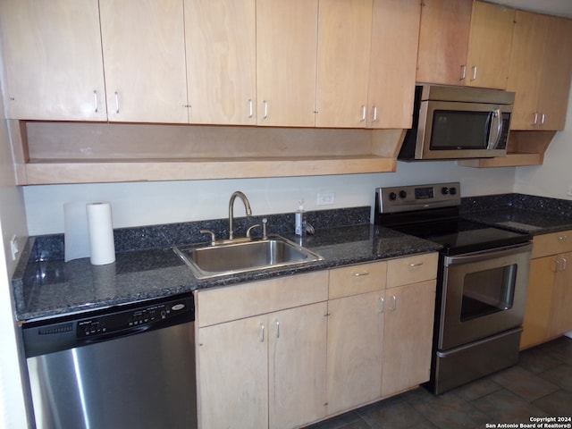 kitchen with light brown cabinetry, sink, appliances with stainless steel finishes, and dark stone countertops