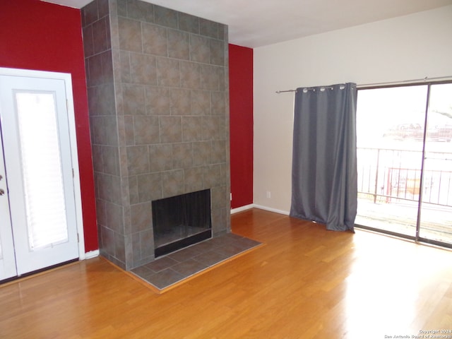 unfurnished living room with a tiled fireplace and hardwood / wood-style flooring