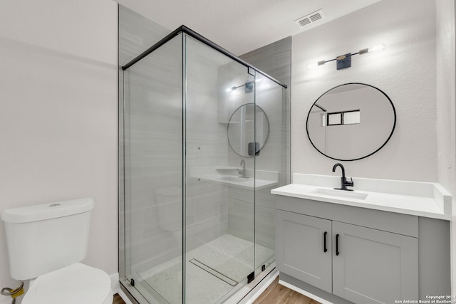 bathroom featuring toilet, a shower with shower door, vanity, and wood-type flooring