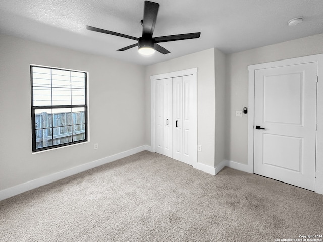 unfurnished bedroom featuring a closet, carpet floors, a textured ceiling, and ceiling fan