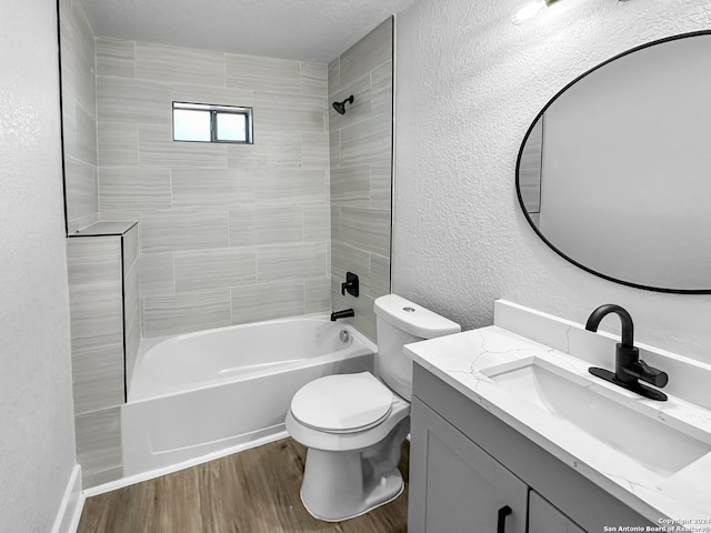 full bathroom with a textured ceiling, wood-type flooring, toilet, vanity, and tiled shower / bath combo