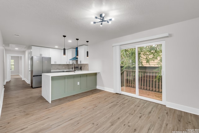 kitchen with white cabinetry, kitchen peninsula, stainless steel fridge, and light wood-type flooring