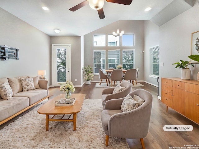 living room with wood-type flooring, ceiling fan with notable chandelier, and vaulted ceiling