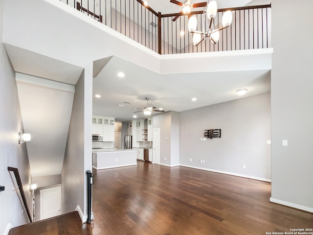 unfurnished living room featuring a chandelier, a high ceiling, and dark hardwood / wood-style flooring