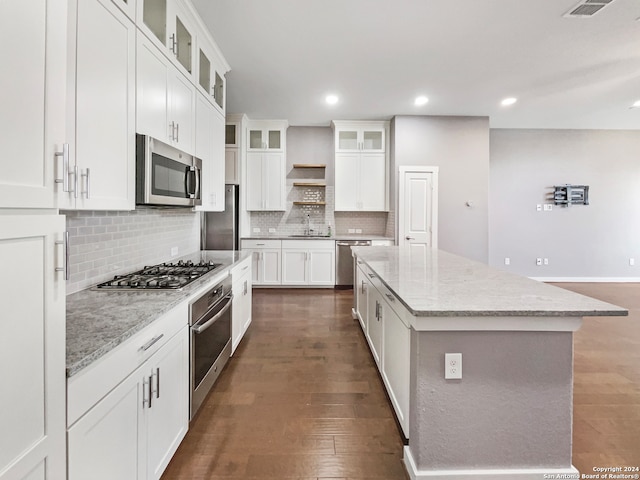 kitchen featuring a kitchen island, stainless steel appliances, white cabinets, light stone counters, and dark hardwood / wood-style flooring