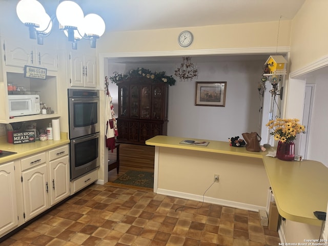 kitchen with double oven, kitchen peninsula, a notable chandelier, decorative light fixtures, and white cabinets