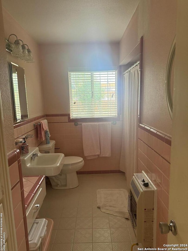 bathroom featuring toilet, tile walls, heating unit, and tile patterned flooring