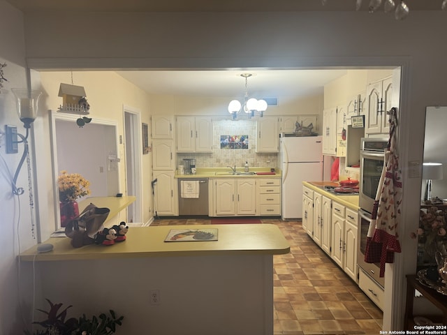 kitchen with decorative backsplash, hanging light fixtures, stainless steel appliances, sink, and a chandelier