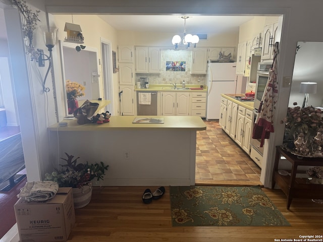 kitchen with appliances with stainless steel finishes, sink, backsplash, pendant lighting, and an inviting chandelier