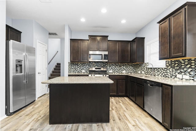 kitchen featuring stainless steel appliances, a kitchen island, sink, and dark brown cabinetry