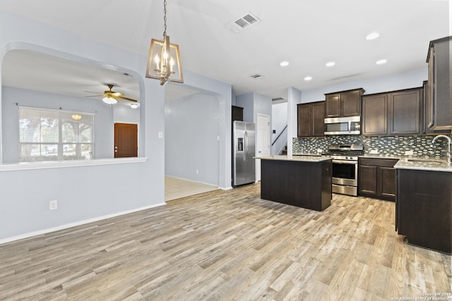 kitchen featuring a kitchen island, tasteful backsplash, ceiling fan, light hardwood / wood-style floors, and stainless steel appliances